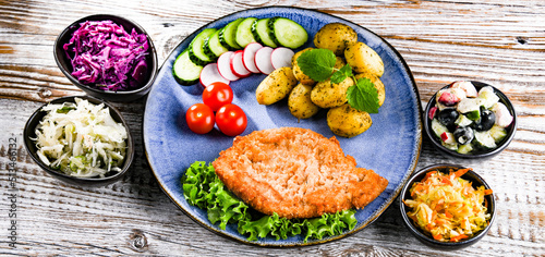 Pork cutlet coated with breadcrumbs with potatoes and salads