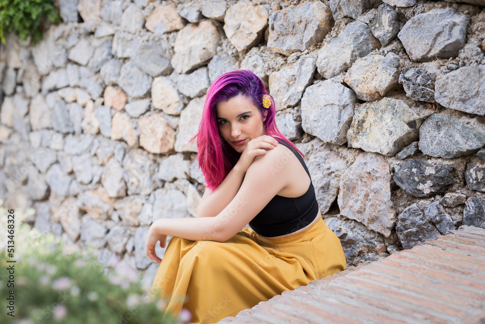 Young woman sitting on stone wall