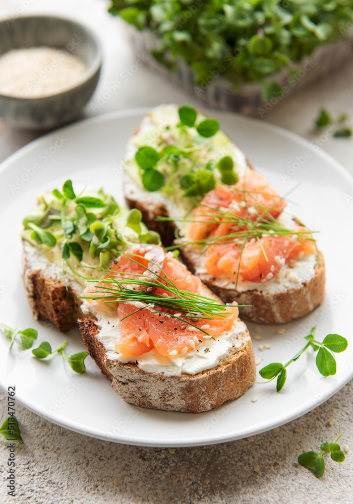 Sandwiches with salted salmon,  avocado and microgreens.