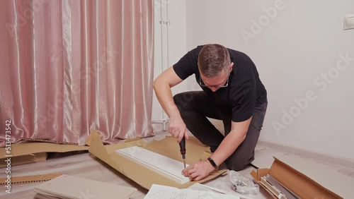 men's hands collect a chest of drawers, screw something with a screwdriver, assembling furniture at home.