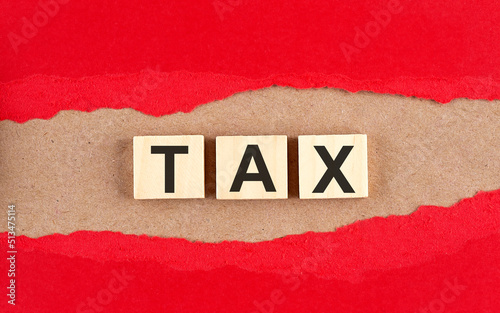 TAX word on wooden cubes on red torn paper , financial concept background