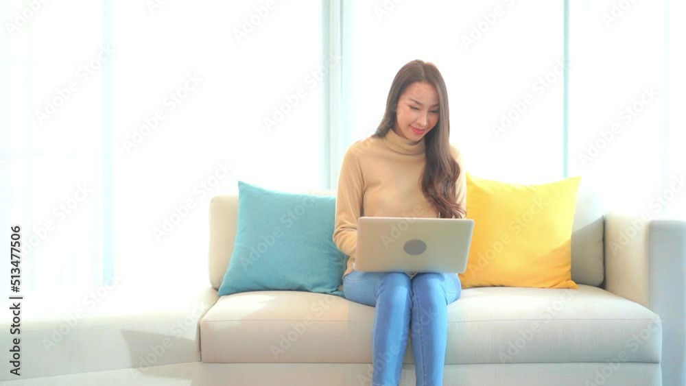 Asian girl with computer sitting on sofa at home Asian girl with computer sitting on sofa at home