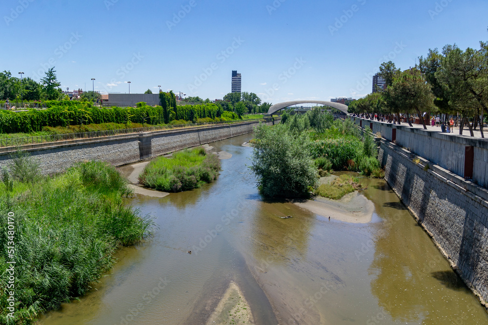 Madrid Rio Park. Views of the Madrid Río park next to the Manzanares river and green vegetation around it. Roads with bridges and footbridges. Fountains with water jets, in Spain. Europe. Photography.