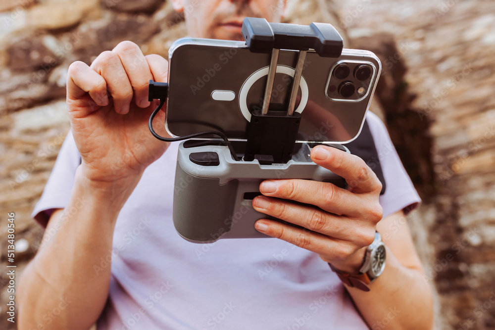 Close up portrait of operator hands holding and using remote controller of drone and smartphone. Technology concept. Close up portrait of operator hands holding and using remote controller of drone and smartphone. Technology concept.