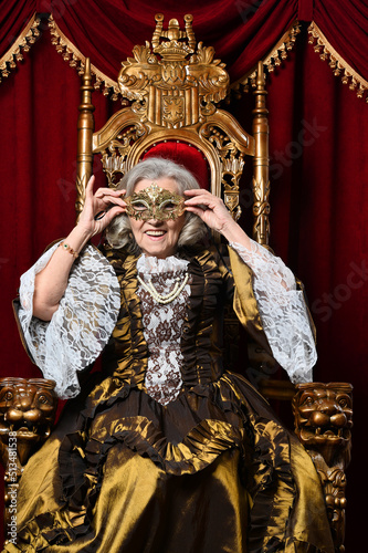 Happy beautiful senior queen with mask on throne