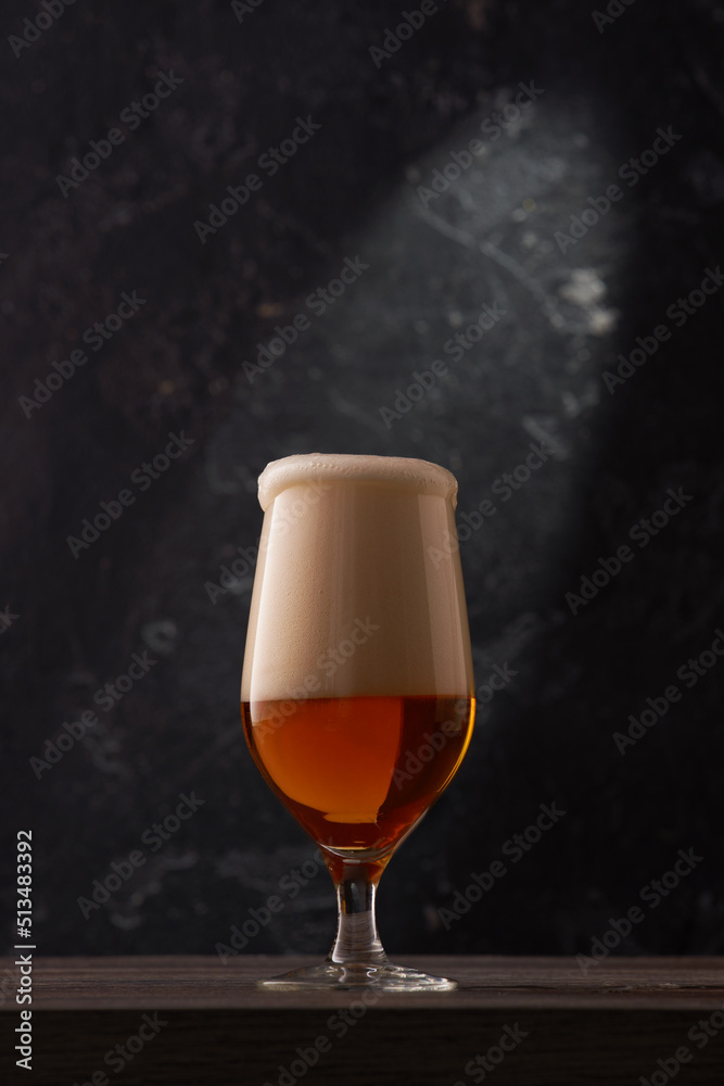 Tulip glass of beer on black background.