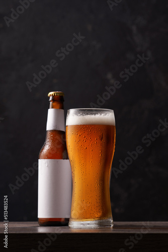 Bottle and glass of beer on black background.