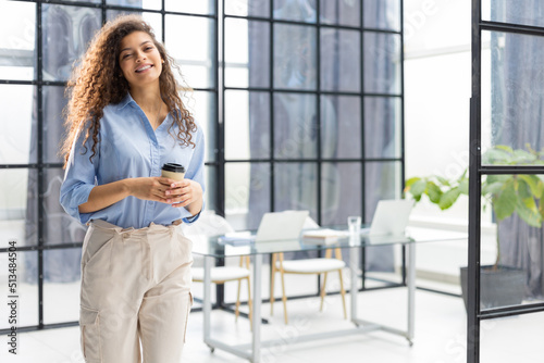 Attractive business woman looking at camera and smiling while standing in the office.