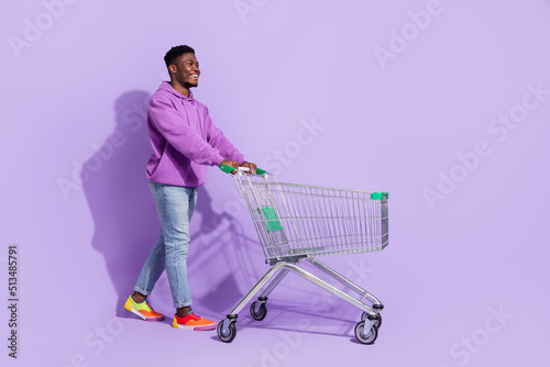 Full size profile portrait of positive person push trolley look empty space isolated on violet color background photo