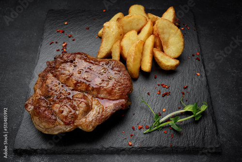 Meat steak on a black stone with fried potatoes