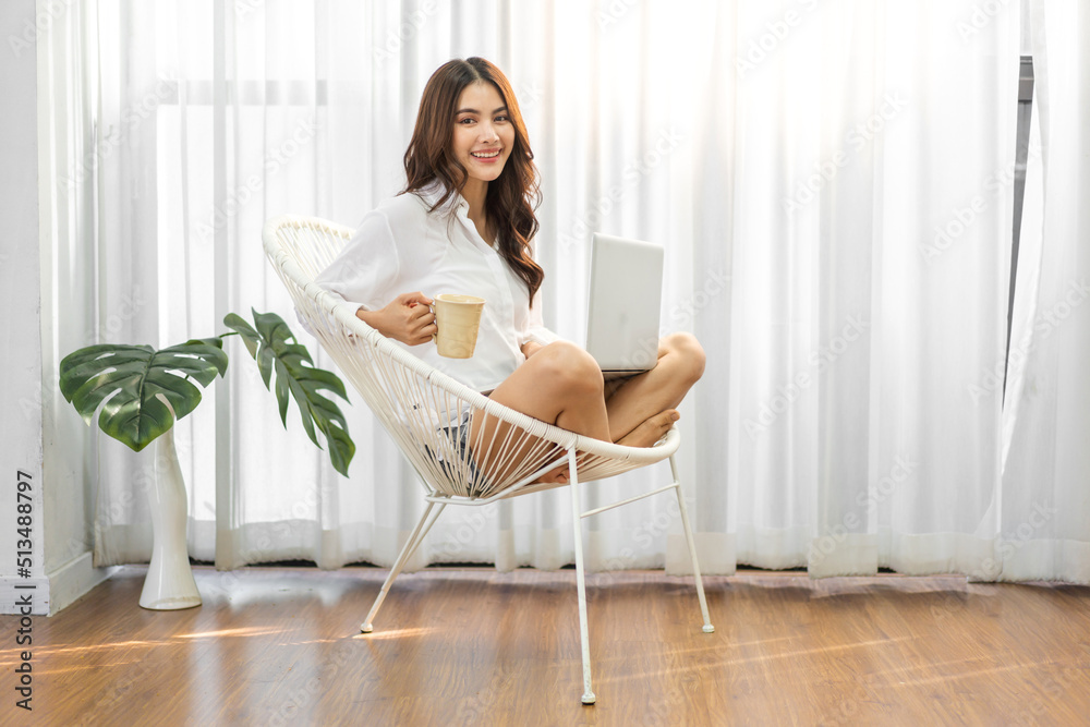 Young smiling happy beautiful asian woman relaxing using laptop computer in the bedroom at home.Young creative girl working and typing on keyboard.work from home concept Young smiling happy beautiful asian woman relaxing using laptop computer in the bedroom at home.Young creative girl working and typing on keyboard.work from home concept