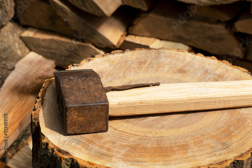 The ax lies on a log next to the firewood