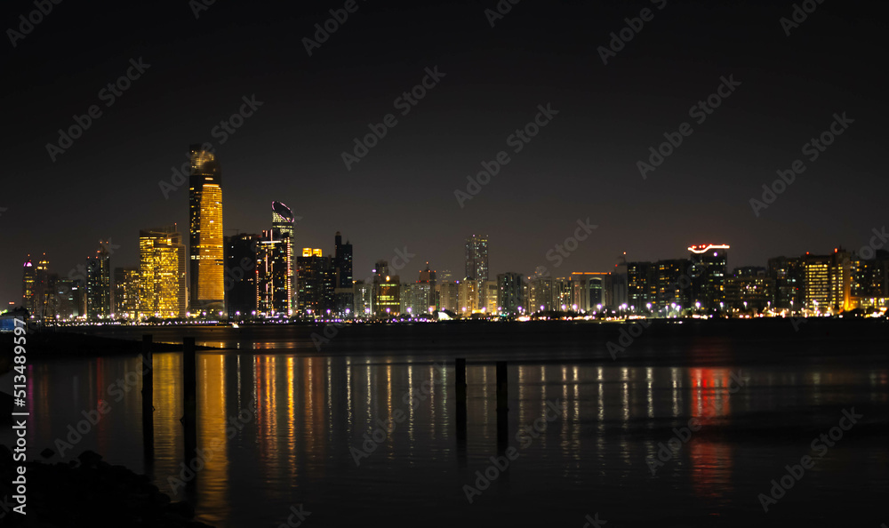 Abu Dhabi skyline and its reflection in water at night