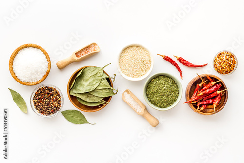 Colorful herbs and spices in bowls for cooking. Pepper chili, laurel leaf, salt and curry