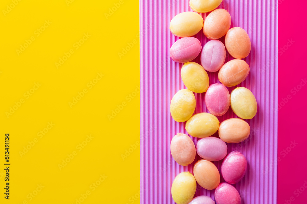Obraz premium Flat lay with lollipops on textured pink and yellow surface.