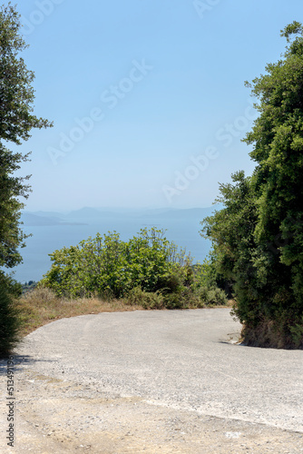 Scenic, narrow road in the mountains with a sharp turn and a view of the sea