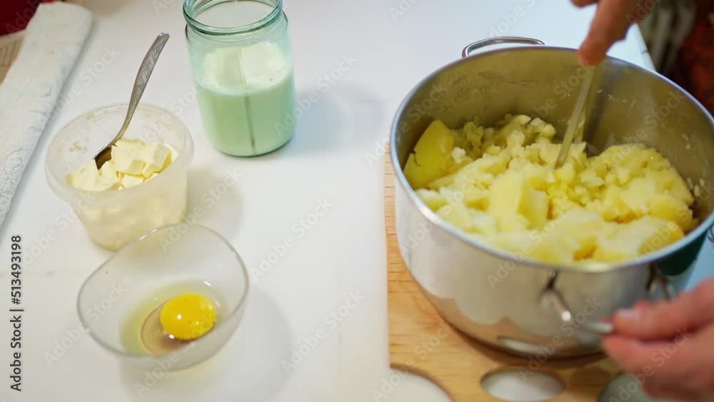 female hands prepare mashed potatoes, knead potatoes in a saucepan with a pusher female hands prepare mashed potatoes, knead potatoes in a saucepan with a pusher