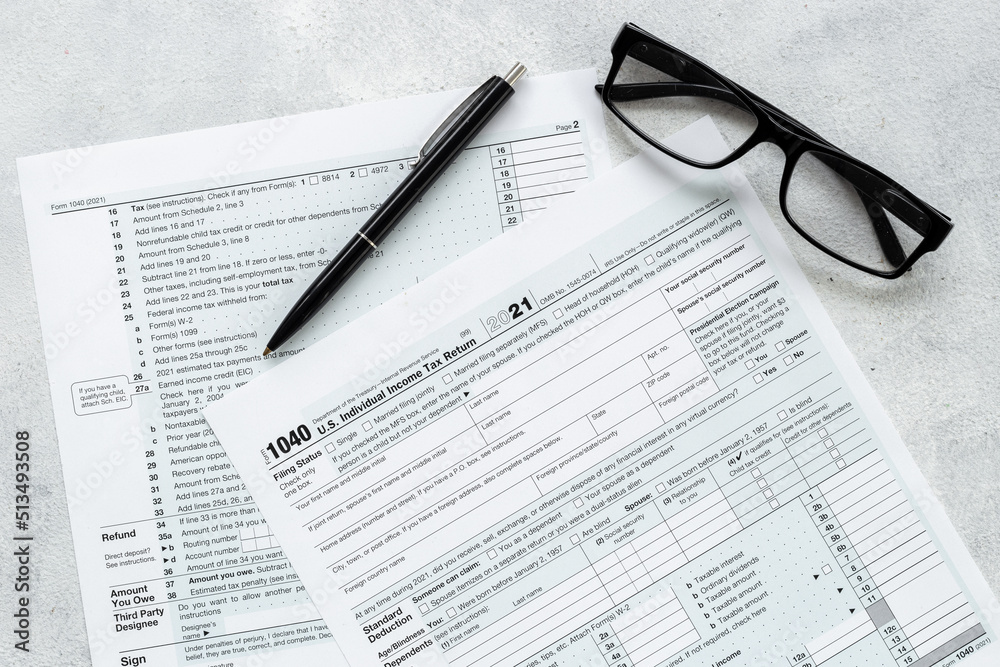 US individual tax form with pen and glasses on businessman table US individual tax form with pen and glasses on businessman table