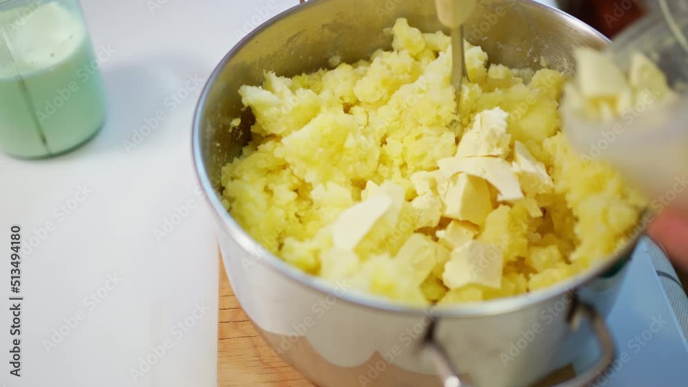 female hands prepare mashed potatoes, mix mashed boiled potatoes with a crush and add pieces of butter there female hands prepare mashed potatoes, mix mashed boiled potatoes with a crush and add pieces of butter there