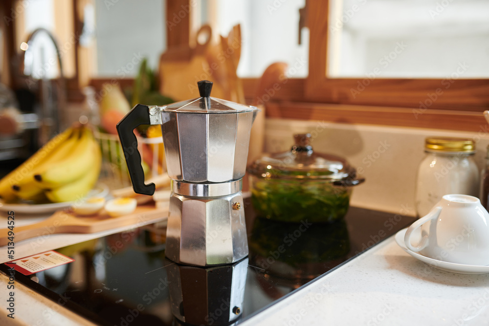 Moka pot on stove in kitchen, morning routine concept Moka pot on stove in kitchen, morning routine concept