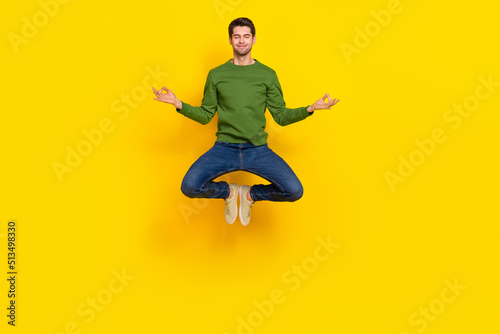 Photo of dreamy cute guy dressed green pullover jumping high practicing yoga isolated yellow color background