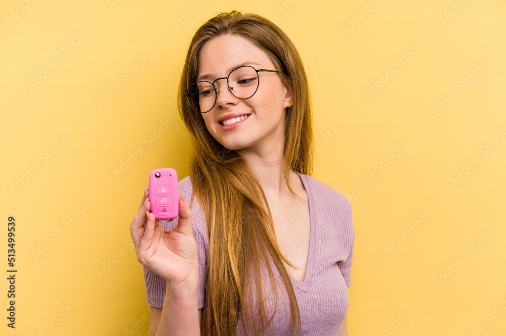 Young caucasian woman holding car keys isolated on yellow background looks aside smiling, cheerful and pleasant. Young caucasian woman holding car keys isolated on yellow background looks aside smiling, cheerful and pleasant.