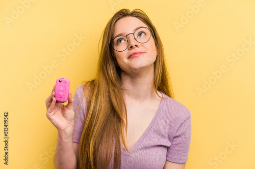 Young caucasian woman holding car keys isolated on yellow background dreaming of achieving goals and purposes