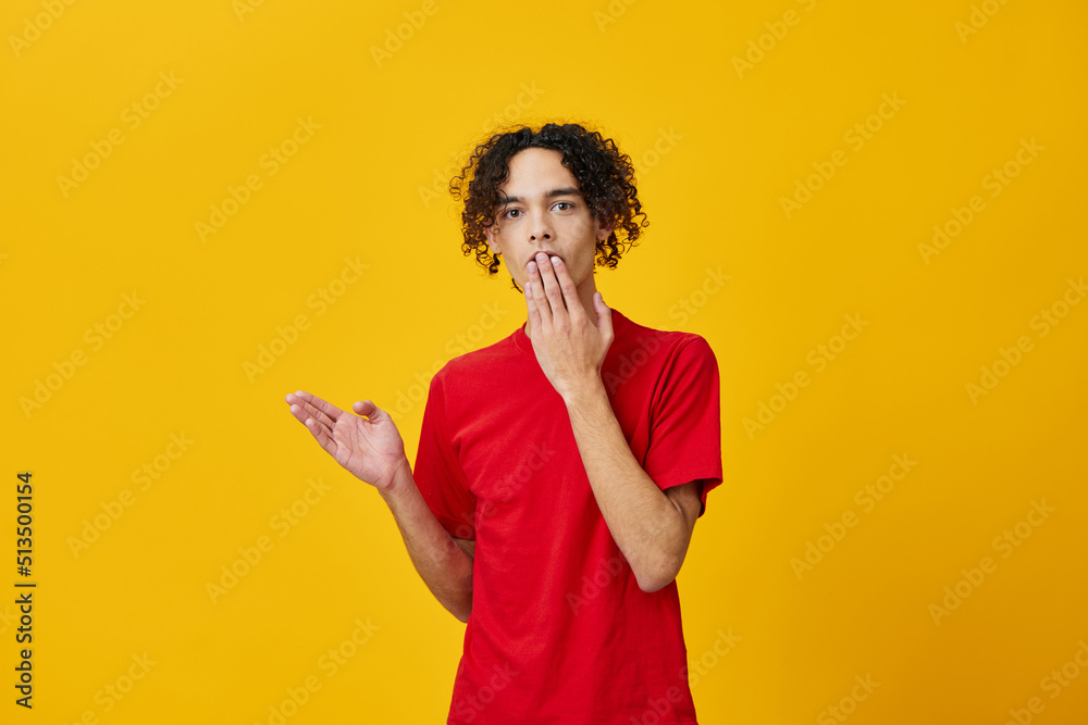 Shocked funny Caucasian young man in red t-shirt point finger aside posing isolated on over yellow studio background. The best offer with free place for advertising. Emotions for everyday concept