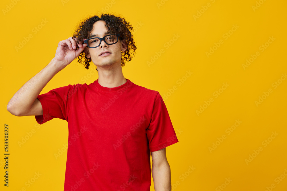 Cute attractive myopic young student man in red t-shirt hold funny eyewear posing isolated on over yellow studio background. The best offer with free place for advertising. Education College concept Cute attractive myopic young student man in red t-shirt hold funny eyewear posing isolated on over yellow studio background. The best offer with free place for advertising. Education College concept