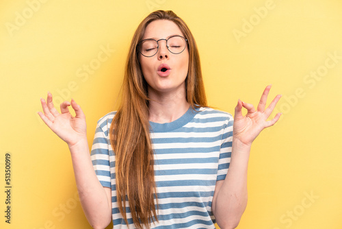 Young caucasian woman isolated on yellow background relaxes after hard working day, she is performing yoga.