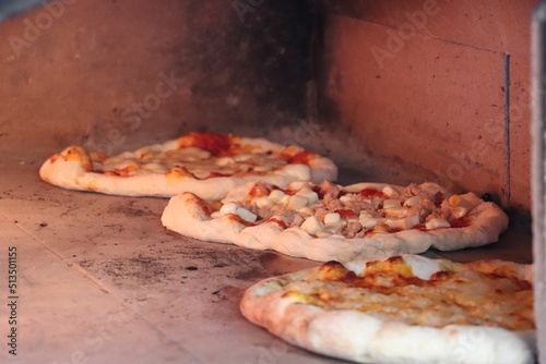 Closeup of pizzas being cooked in a traditional wood oven in Fruili, Italy photo