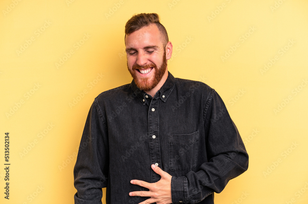 Obraz premium Young caucasian man isolated on yellow background touches tummy, smiles gently, eating and satisfaction concept.