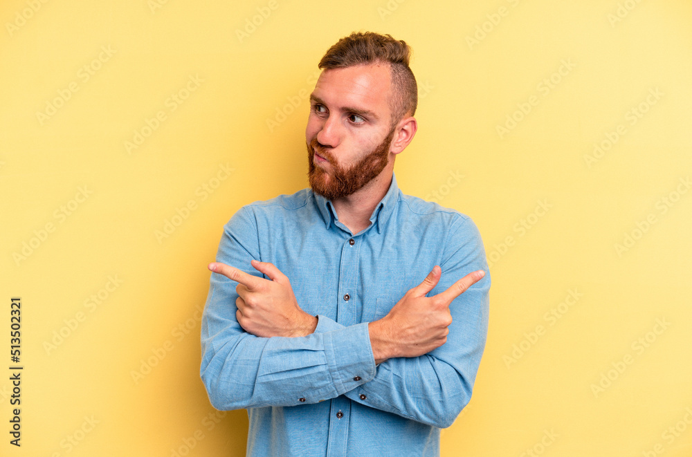 Young caucasian man isolated on yellow background points sideways, is trying to choose between two options. Young caucasian man isolated on yellow background points sideways, is trying to choose between two options.