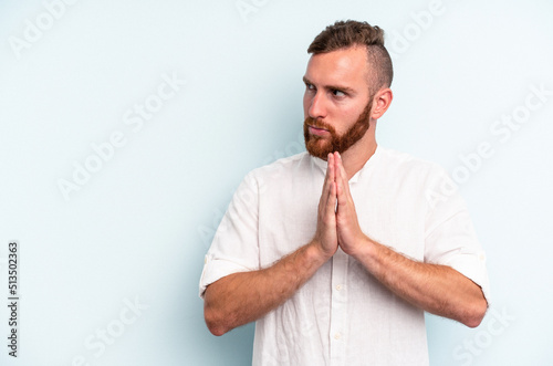 Young caucasian man isolated on blue background making up plan in mind, setting up an idea.