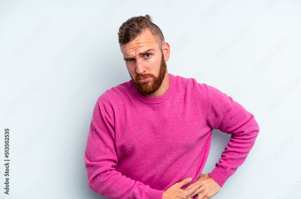 Obraz premium Young caucasian man isolated on blue background having a liver pain, stomach ache.