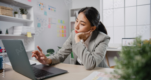 Photos Young Asian businesswoman sit on desk with laptop overworked tired burnout syndrome at office