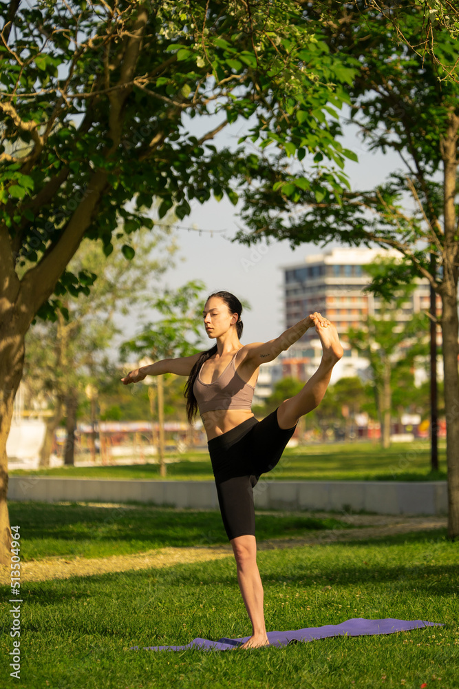 Athletic young woman doing yoga in the Park in the morning.