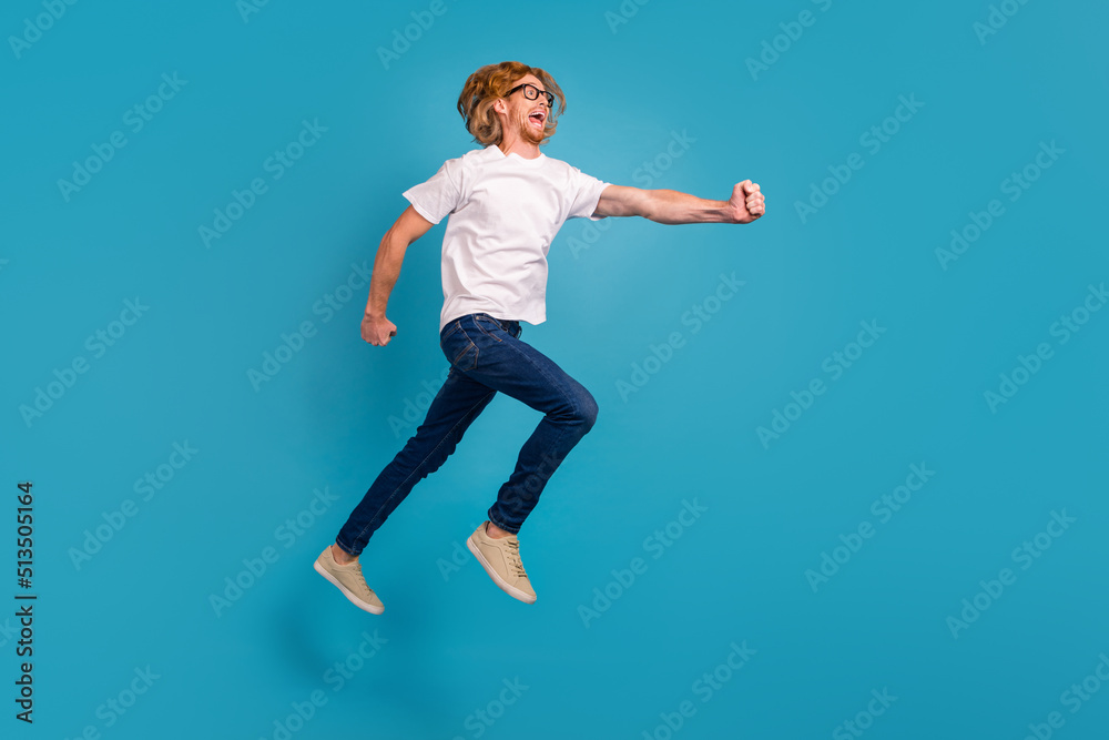 Full size profile portrait of cheerful overjoyed man jump hurry run empty space isolated on blue color background