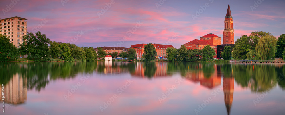 Kiel, Germany. Panoramic cityscape image of downtown Kiel, Germany with Town Hall, Opera House and reflection of the skyline in Small Kiel at sunset.