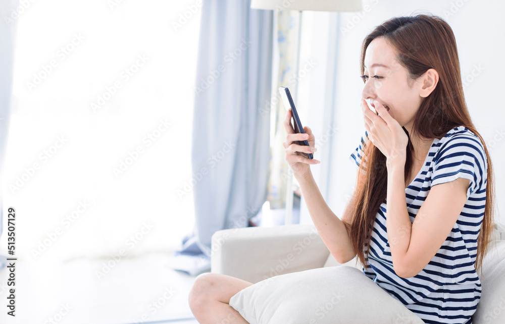 Surprised young woman looking at smartphone screen on the sofa at home Surprised young woman looking at smartphone screen on the sofa at home