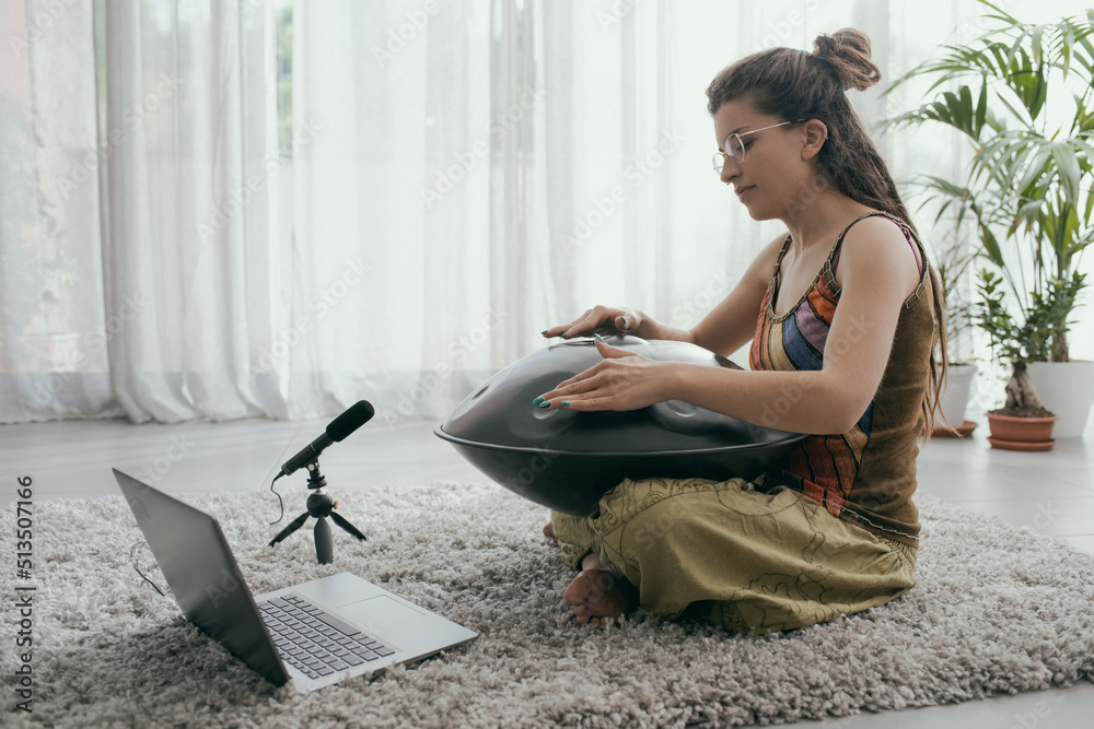 Fototapeta premium Woman playing a hang drum and recording