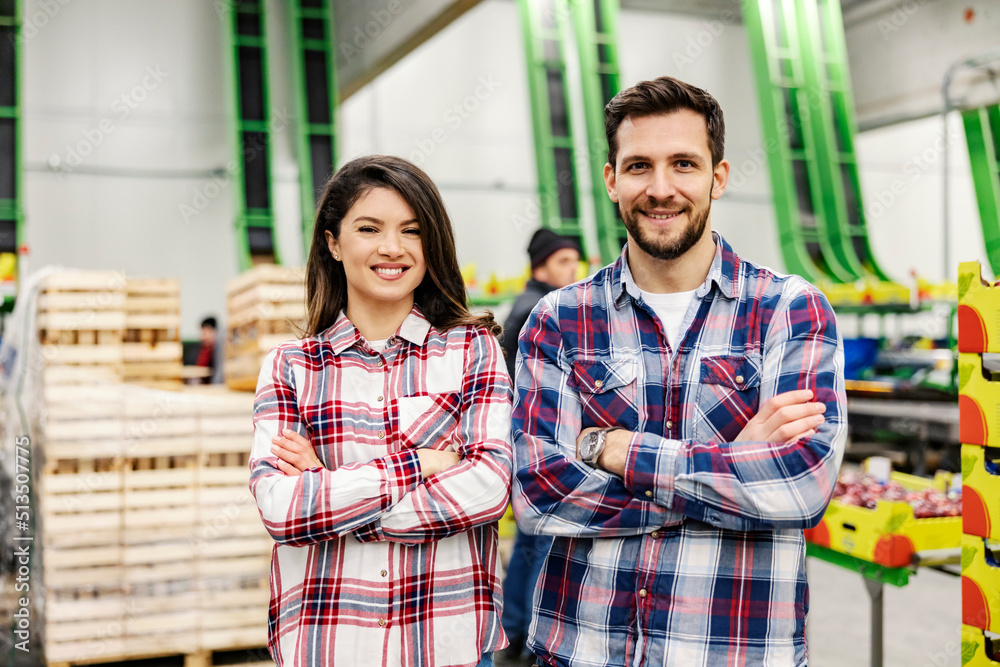 Two managers standing in food factory storage and smiling at the camera. Two managers standing in food factory storage and smiling at the camera.