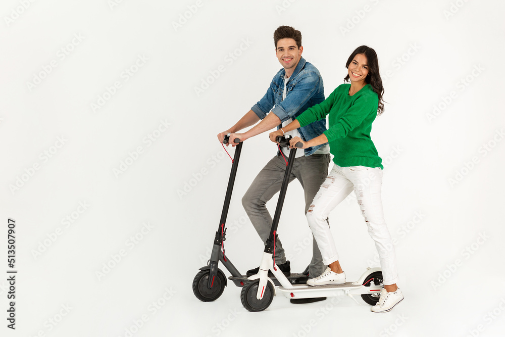 a couple riding on electic kick scooter isolated on white studio background a couple riding on electic kick scooter isolated on white studio background