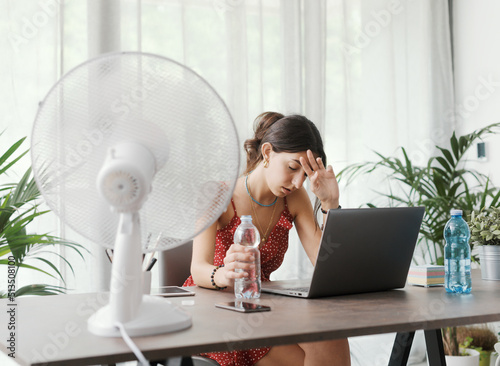 Woman cooling herself with an electric fan photo