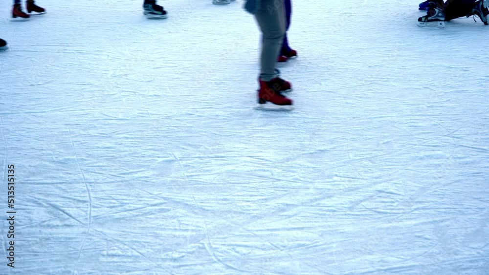 Ice skating rink in winter. People are skating. Skates ride on ice. Ice