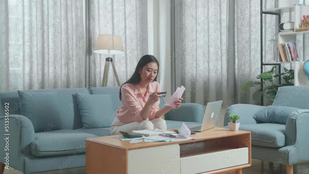 Asian Woman With A Laptop Looking At Bill And Credit Card Shaking His Head Then Having Headache  
