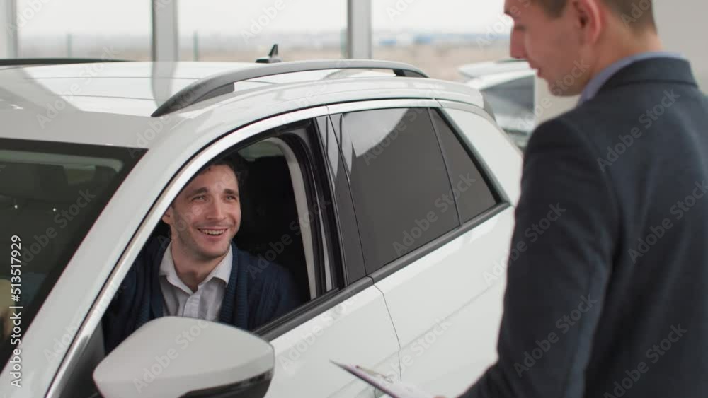 automobile show, sales manager shaking hands male customer in auto inside, buyer is choosing automobile in dealership automobile show, sales manager shaking hands male customer in auto inside, buyer is choosing automobile in dealership