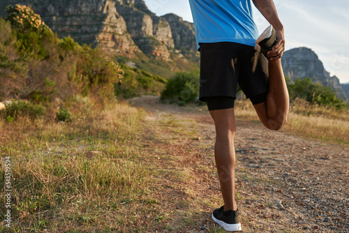 African American Black young Adult male stretching his leg after his outdoor trail run. Beautiful view of mountain in the background © Sarah