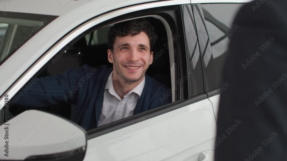 portrait of happy young man takes keys to new car from manager, rejoices in a purchase in automobile dealership portrait of happy young man takes keys to new car from manager, rejoices in a purchase in automobile dealership