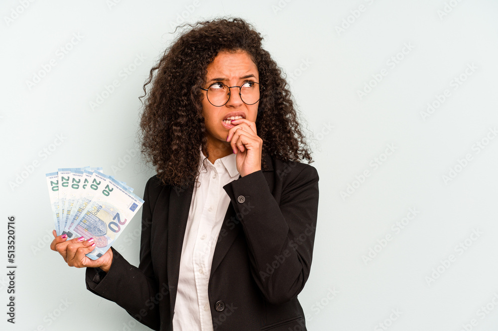 Young business Brazilian woman holding banknotes isolated on white background relaxed thinking about something looking at a copy space. Young business Brazilian woman holding banknotes isolated on white background relaxed thinking about something looking at a copy space.